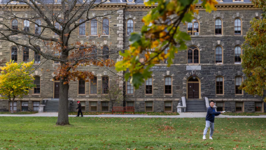 A student throws a frisbee on a field at Cornell University.