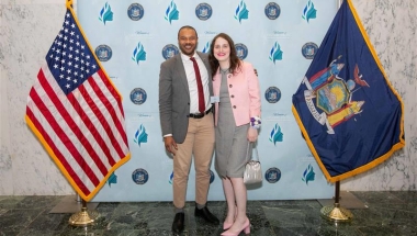 Sen. Jabari Brisport stands with Ms. Abby Stein between a US flag and a New York State flag